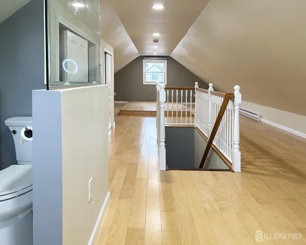 a view of a hallway with wooden floor and a bathroom view