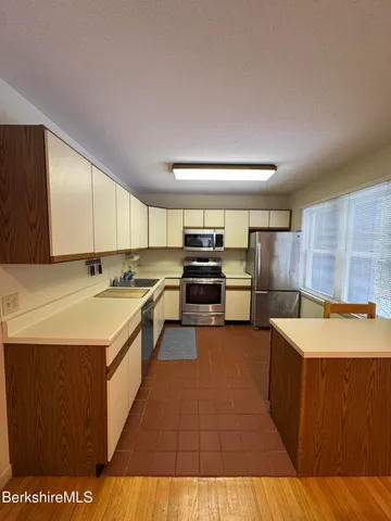 a large kitchen with stainless steel appliances granite countertop a large counter top a stove and a sink