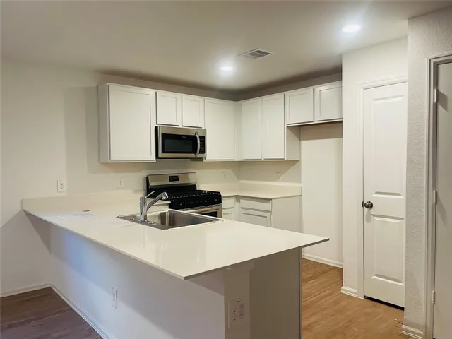 a kitchen with a refrigerator a microwave a sink and cabinets