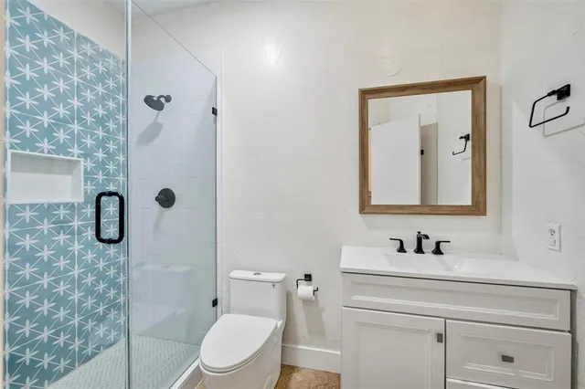 a bathroom with a granite countertop sink toilet a mirror and shower