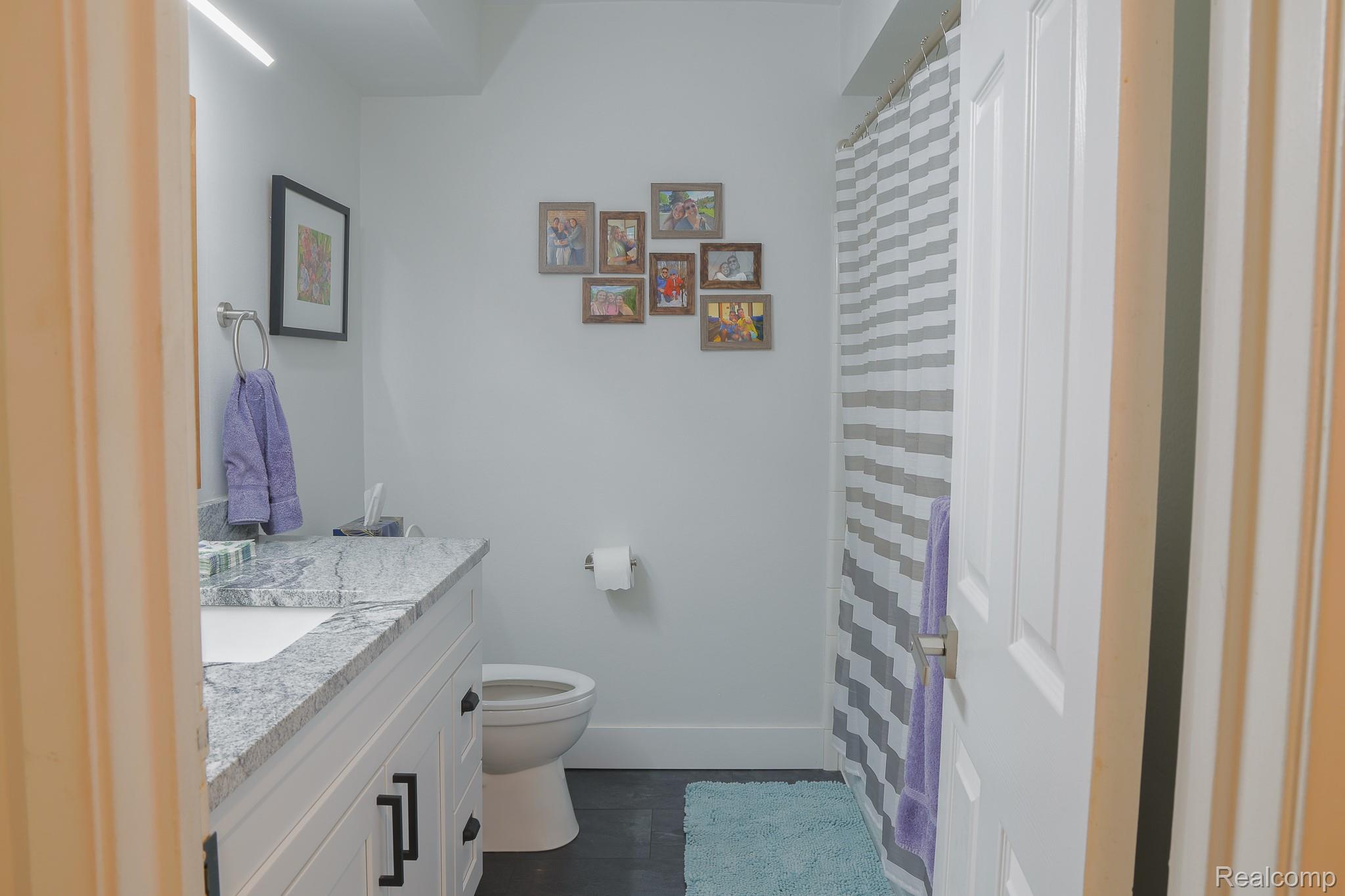 1989 Klingensmith Road, Unit 46 Bloomfield Hills, MI 48302 - Photo 21 of 41 Bathroom featuring a white vanity with a granite-style countertop, undermount sink, and black hardware