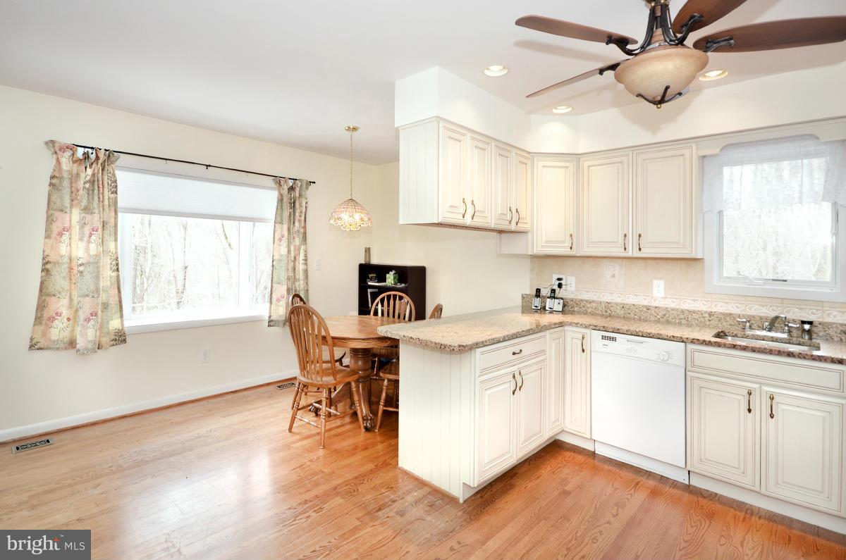 13912 Glen High Road Baldwin, MD 21013 - Photo 21 of 28 a kitchen with stainless steel appliances granite countertop a stove top oven a sink a dining table and chairs with wooden floor