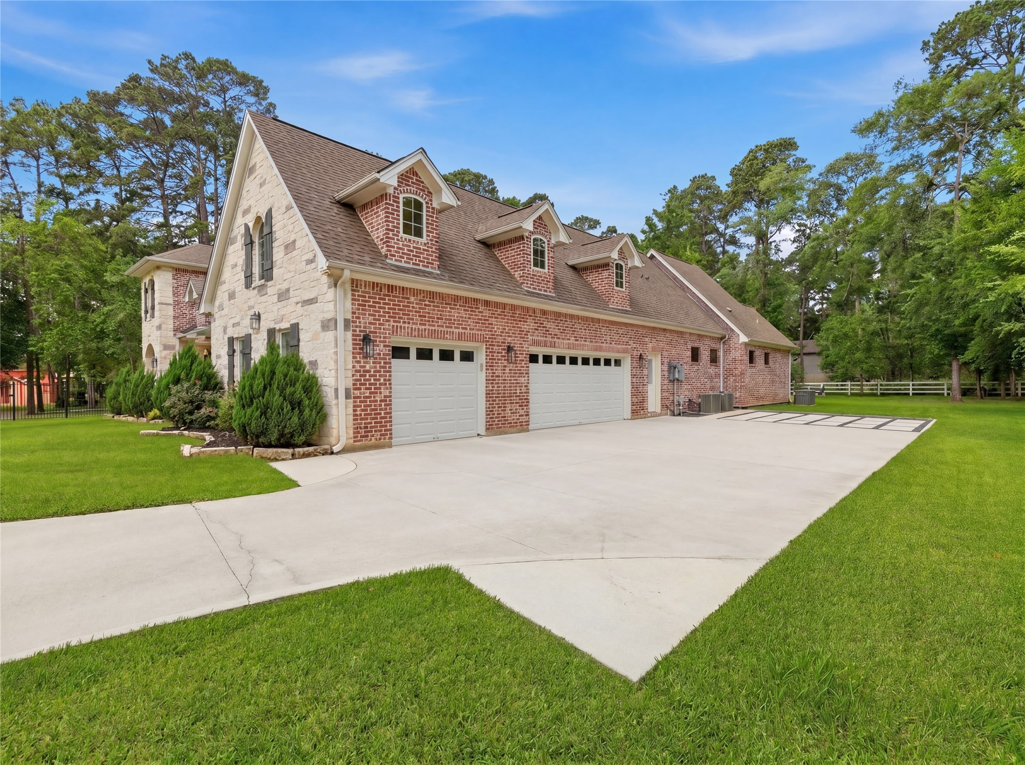 7106 Hampton Court Spring, TX 77389 - Photo 27 of 31 Spacious, two-story brick and stone house with a large driveway and three-car garage. The property features well-maintained landscaping and lush green lawns, surrounded by tall trees, offering a tranquil setting.