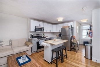 84 Emerson Street, Unit 2 Boston, MA 02127 - Photo 6 of 18 a living room with stainless steel appliances furniture a rug and a kitchen view