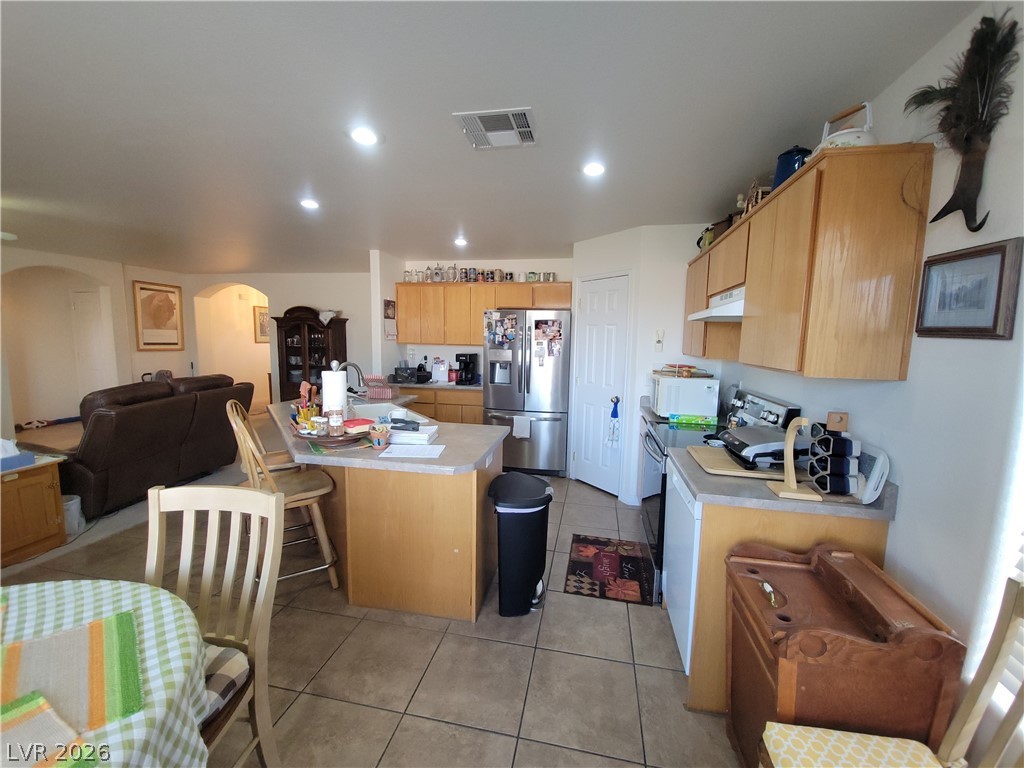 768 Weiser Ridge Street Overton, NV 89040 - Photo 37 of 37 Kitchen featuring open floor plan, stainless steel refrigerator with ice dispenser, light countertops, electric stove, and arched walkways