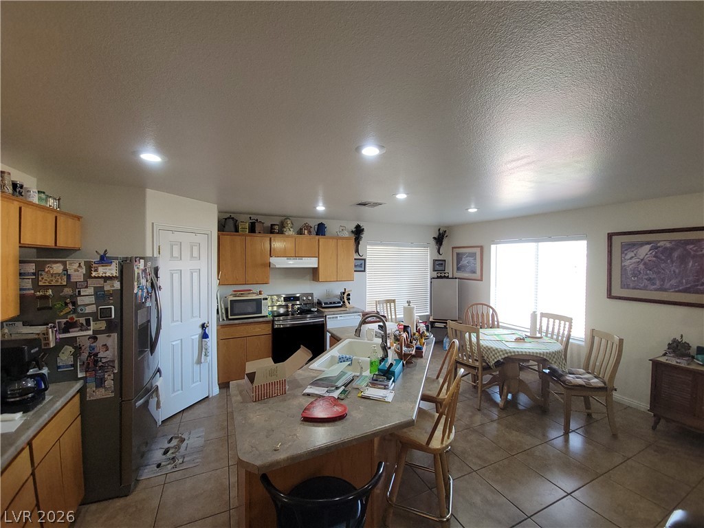 768 Weiser Ridge Street Overton, NV 89040 - Photo 11 of 37 Kitchen with stainless steel appliances, an island with sink, wood finish cabinetry, dark tile patterned floors, and recessed lighting
