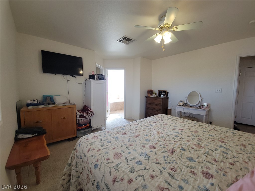 768 Weiser Ridge Street Overton, NV 89040 - Photo 12 of 37 Primary bedroom featuring light colored carpet, a ceiling fan, and connected bathroom