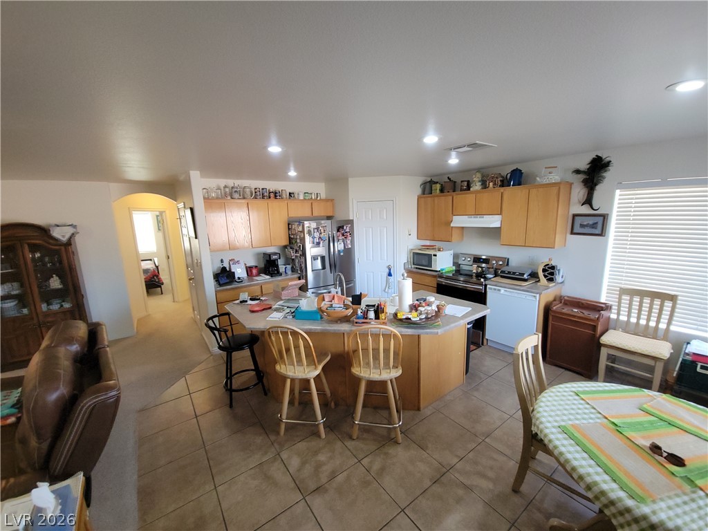 768 Weiser Ridge Street Overton, NV 89040 - Photo 10 of 37 Kitchen with arched walkways, stainless steel appliances, a kitchen island with sink, a breakfast bar area, and dark tile patterned floors