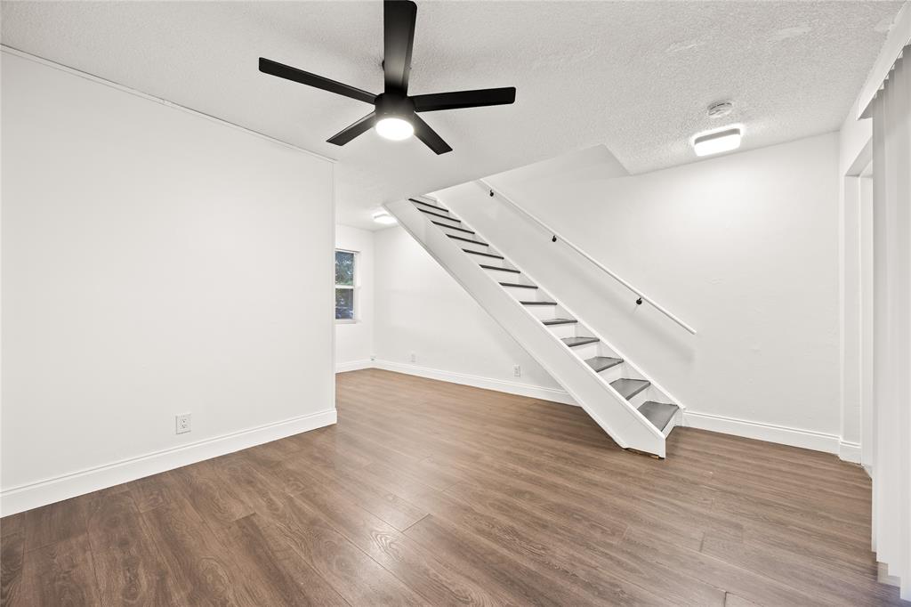1801 Northeast 56th Street, Unit 5 Fort Lauderdale, FL 33308 - Photo 1 of 22 an empty room with wooden floor staircase and windows