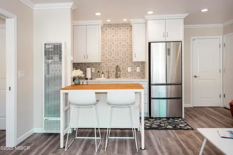 a view of kitchen with stainless steel appliances refrigerator wooden floor dining table and chairs