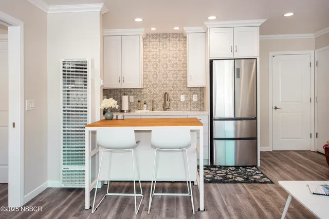 a view of kitchen with stainless steel appliances refrigerator wooden floor dining table and chairs