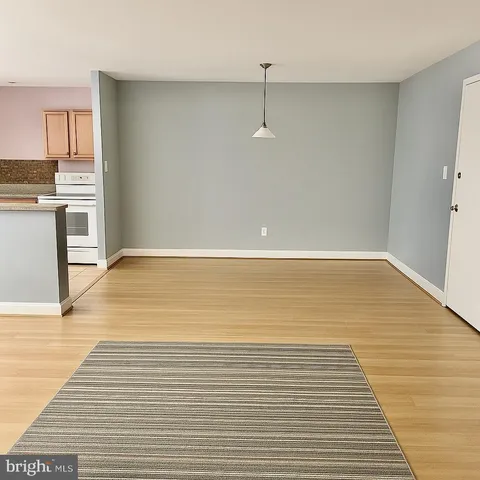 a view of kitchen and empty room with wooden floor