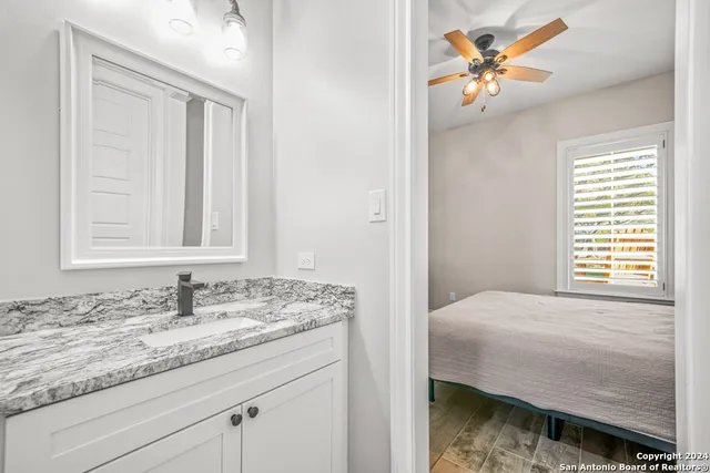 a en suite bathroom with a granite countertop sink and a mirror