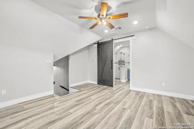 wooden floor in an empty room with a chandelier fan