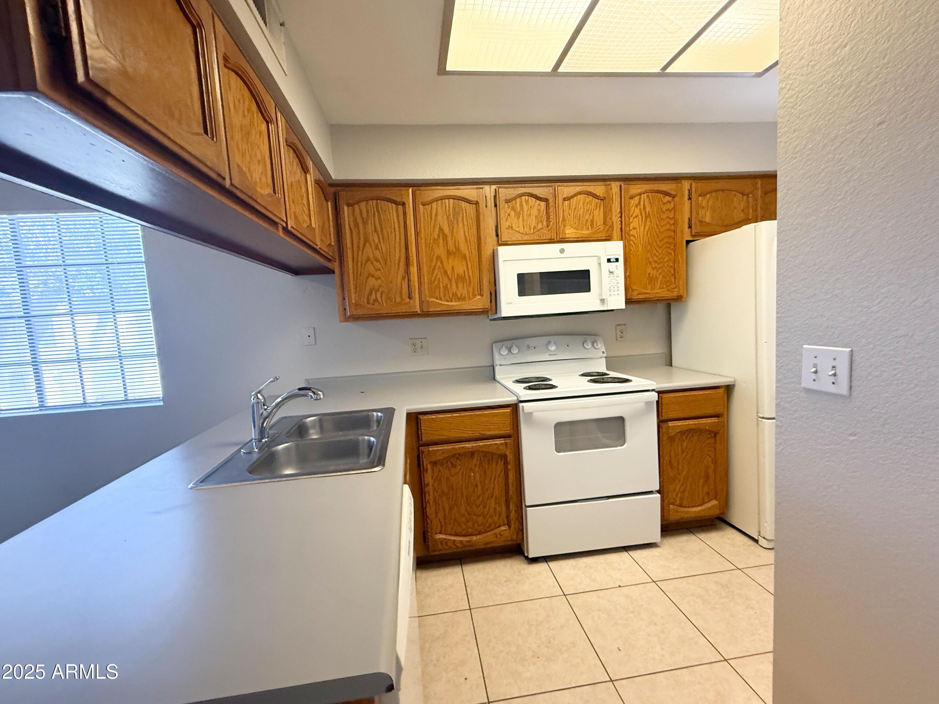 170 East Guadalupe Road, Unit 130 Gilbert, AZ 85234 - Photo 5 of 18 a kitchen with a stove a sink and a microwave