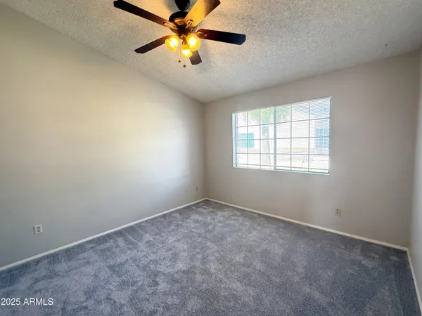 an empty room with windows and chandelier fan