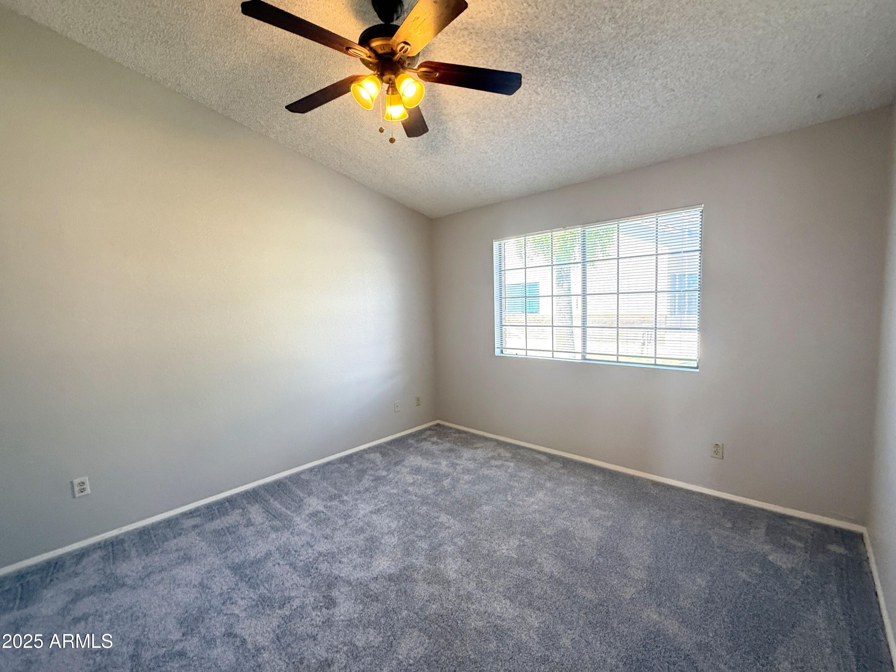 170 East Guadalupe Road, Unit 130 Gilbert, AZ 85234 - Photo 8 of 18 an empty room with windows and chandelier fan