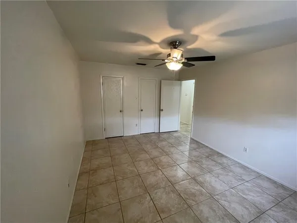 an empty room with a chandelier fan and windows