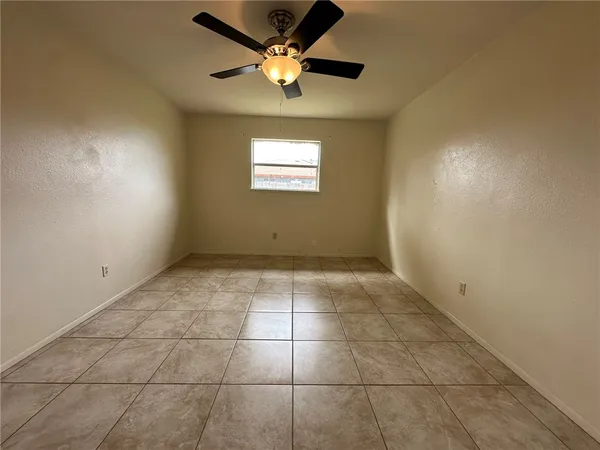 a view of an empty room and a ceiling fan and window