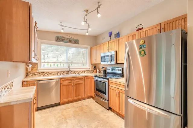 a kitchen with stainless steel appliances granite countertop a refrigerator a sink and white cabinets