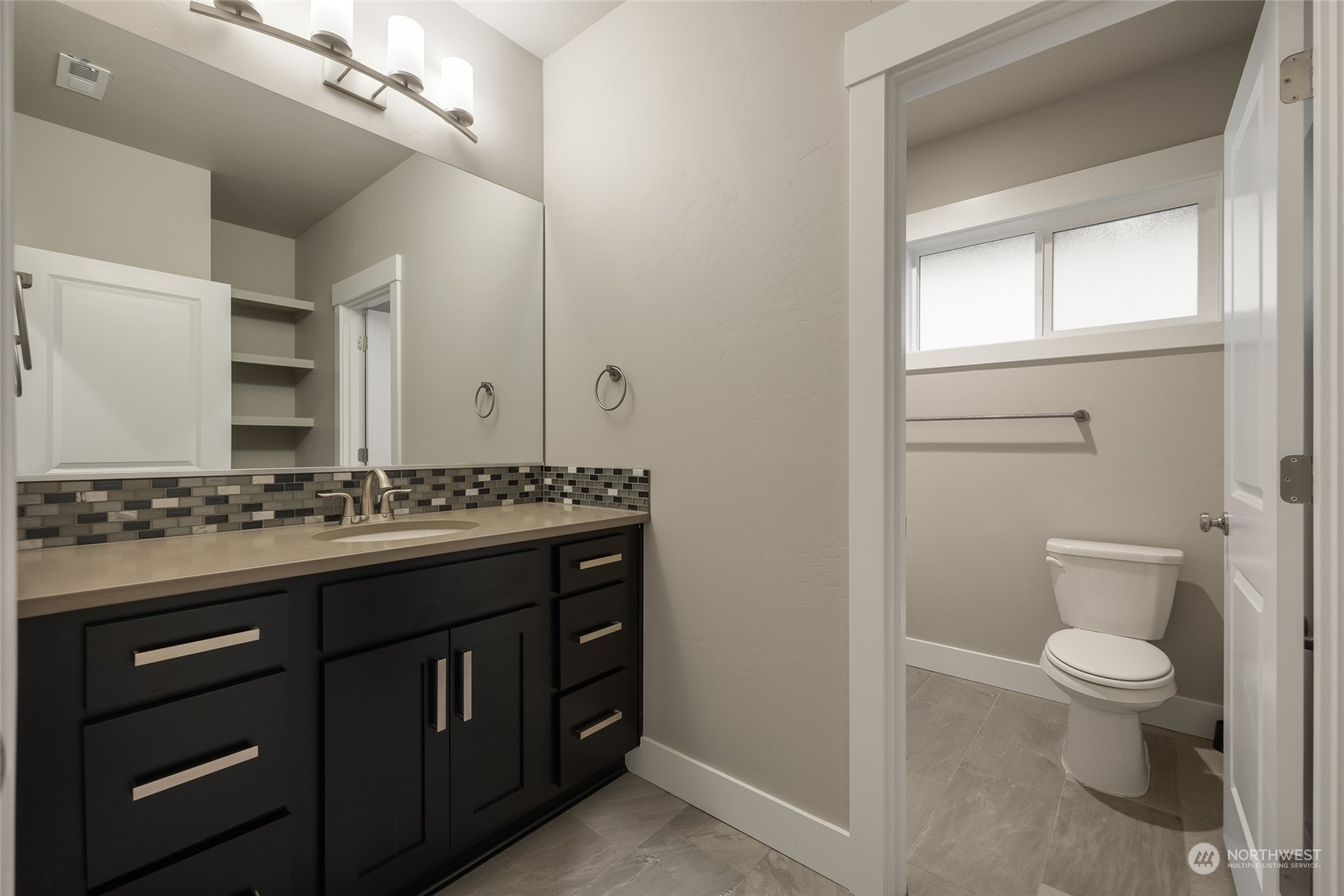5307 South Kent Street Kennewick, WA 99337 - Photo 31 of 40 a bathroom with a granite countertop toilet a sink a mirror and a window