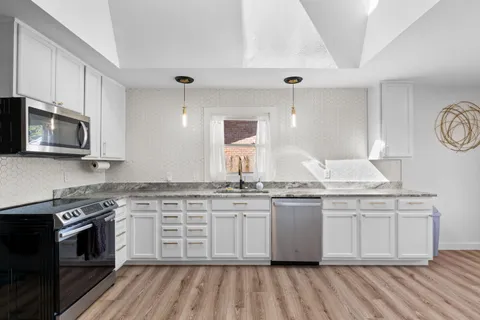 a kitchen with stainless steel appliances granite countertop a stove a sink and a microwave