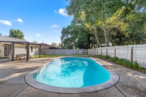 a view of a swimming pool with a yard and plants