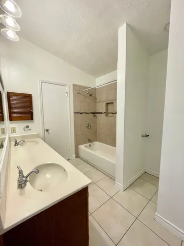 a utility room with a sink a cabinetry and a mirror