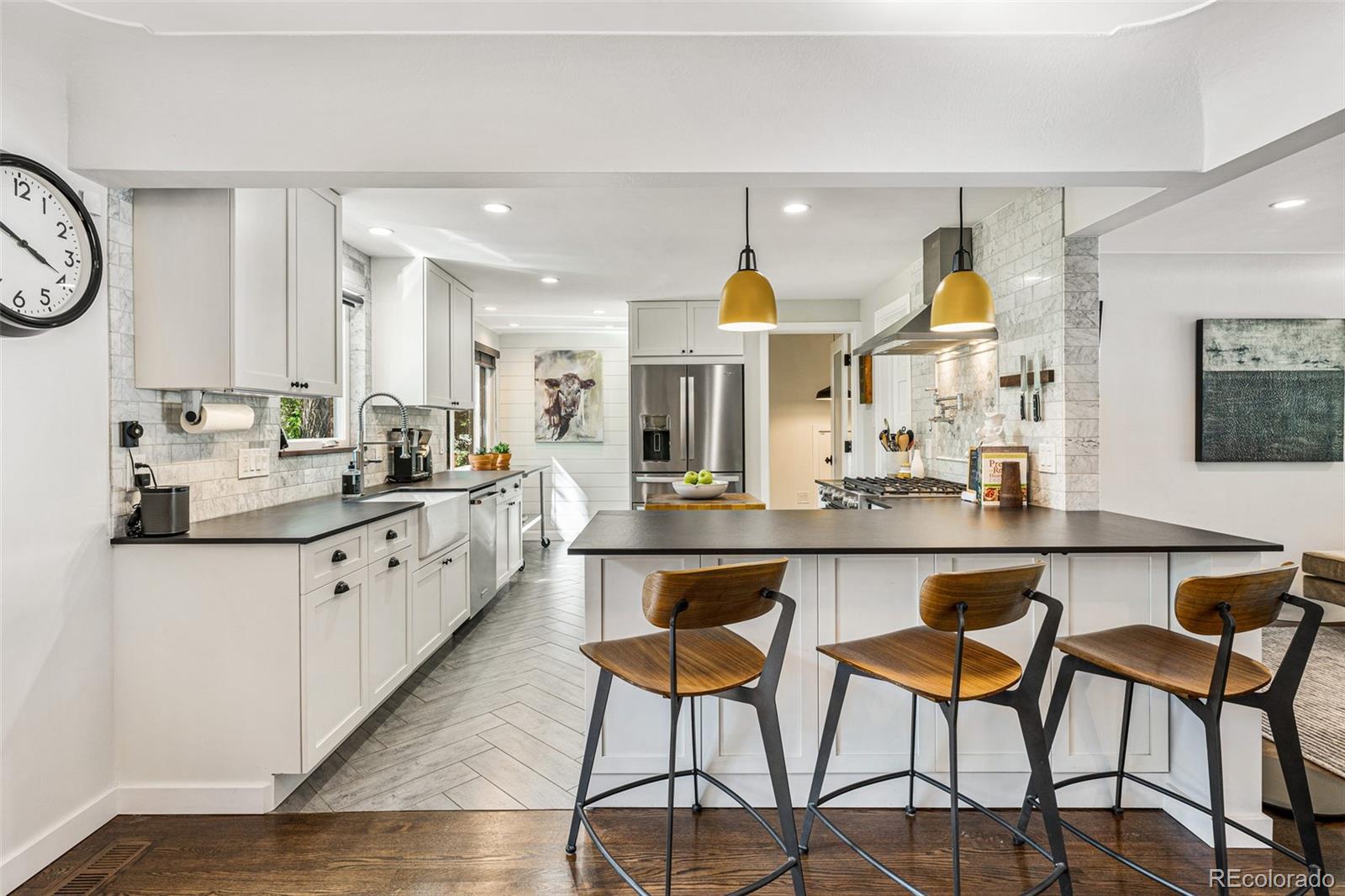 3885 Cody Street Wheat Ridge, CO 80033 - Photo 14 of 40 a kitchen with stainless steel appliances kitchen island granite countertop a table chairs sink and cabinets