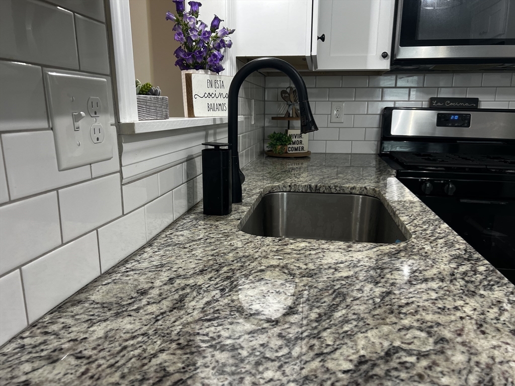 133 Winton Street Springfield, MA 01118 - Photo 7 of 17 a kitchen with granite countertop a sink and a stove