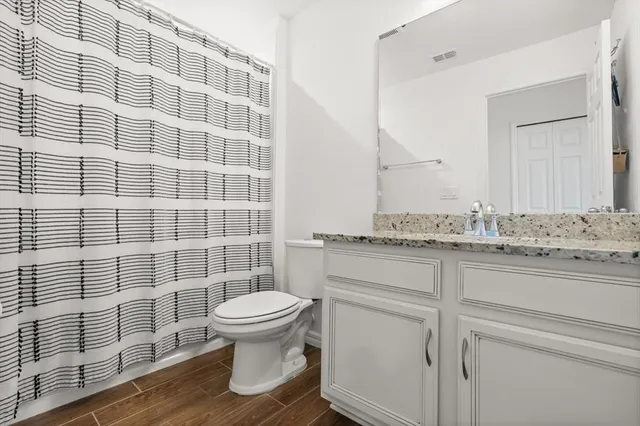 a bathroom with a granite countertop toilet a sink and a shower