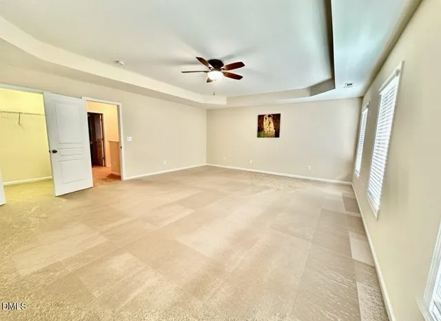 an empty room with ceiling fan and window