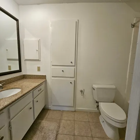 a bathroom with a granite countertop toilet and sink