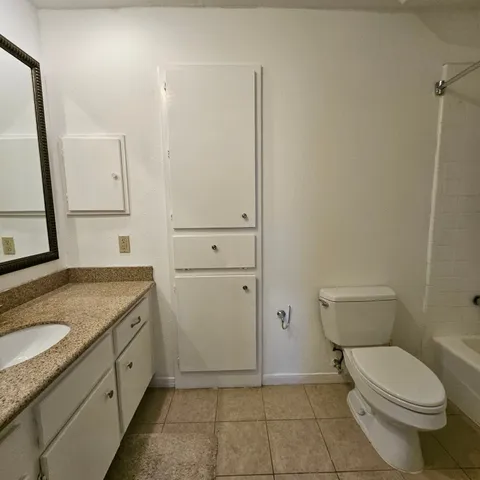 a bathroom with a granite countertop toilet and sink