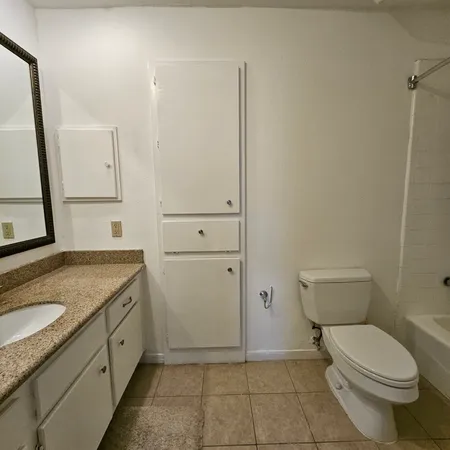 a bathroom with a granite countertop sink toilet and mirror