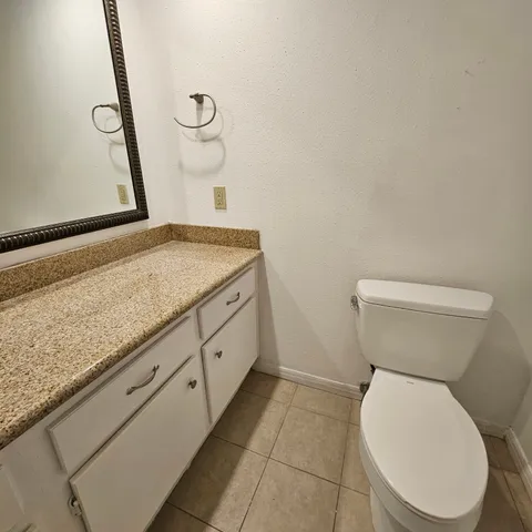 a bathroom with a granite countertop toilet and a sink