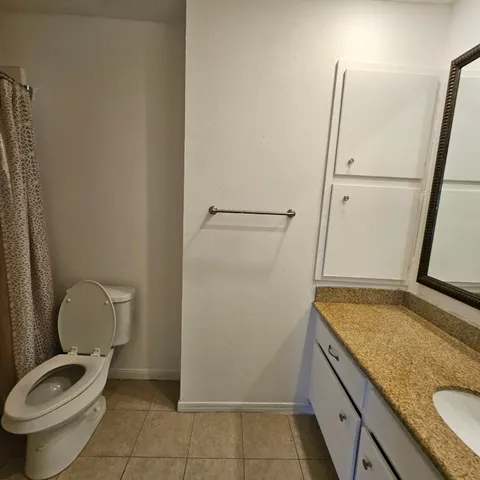 a bathroom with a granite countertop toilet and a sink