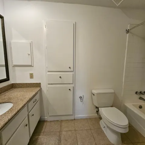 a bathroom with a granite countertop toilet and sink