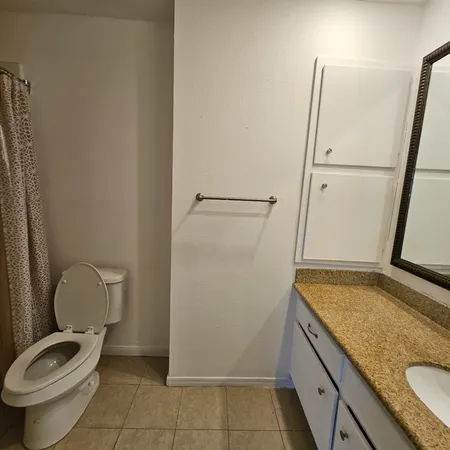 a bathroom with a granite countertop toilet and a sink