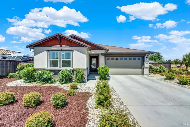 a front view of a house with a yard and potted plants