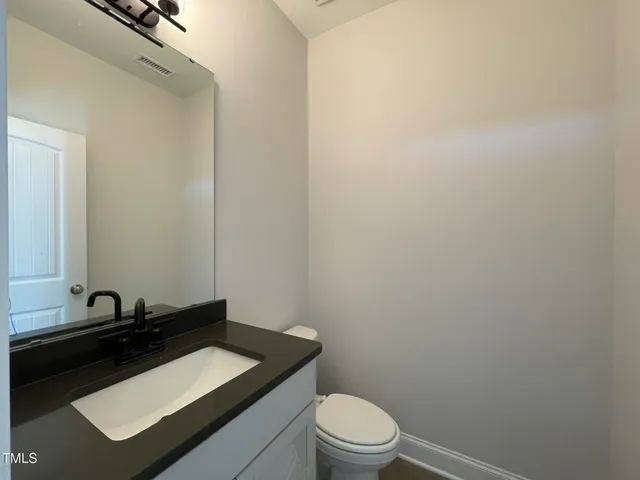a bathroom with a granite countertop toilet sink and mirror