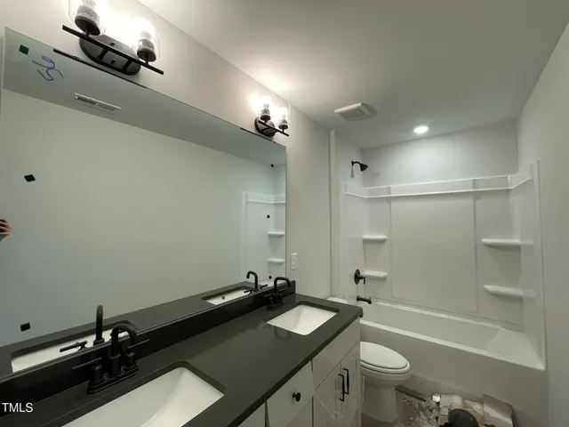 a bathroom with a sink a toilet a mirror and shower