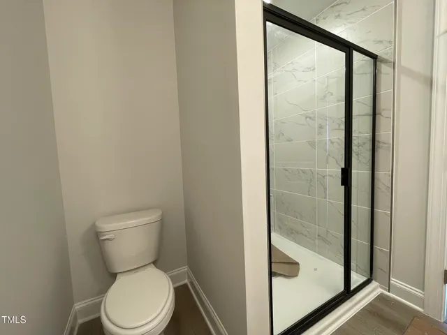 a white toilet sitting next to a shower