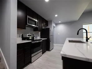 a kitchen with stainless steel appliances granite countertop a sink a stove top oven and wooden floor