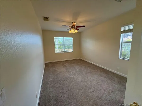 an empty room with windows and fan
