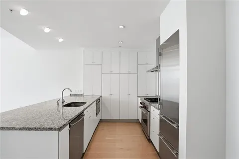 a kitchen with granite countertop kitchen island stainless steel appliances a sink stove and refrigerator