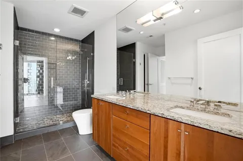 a bathroom with a granite countertop sink a toilet a mirror and shower