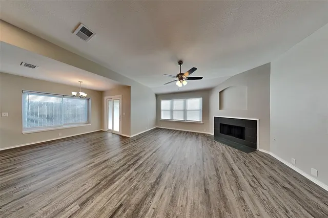 a view of an empty room with wooden floor fireplace and a window