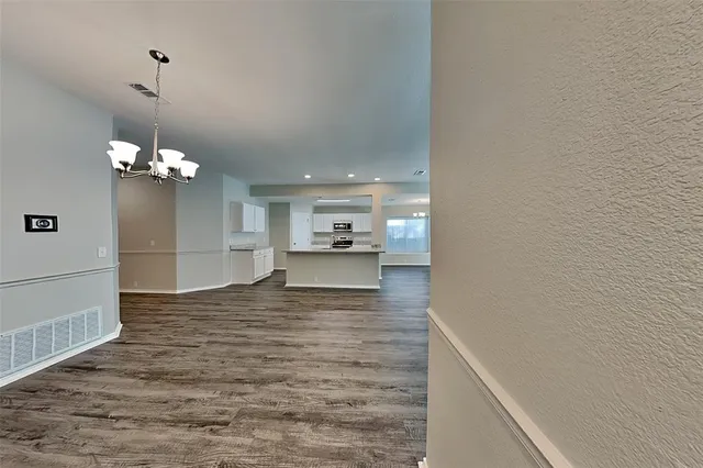 a view of a kitchen with a sink dishwasher a microwave oven and a dining table with wooden floor