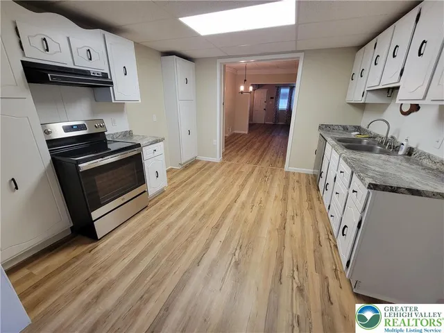 a kitchen with granite countertop a sink a stove and cabinets